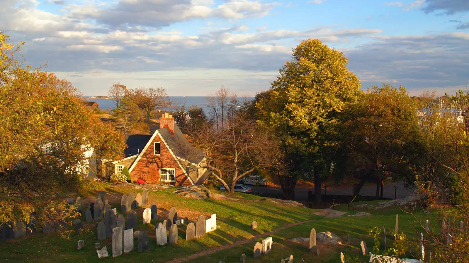 Slate gravestones on the slope of Old Burial Hill, Marblehead, with the harbour behind – the cemetery of the Hocus Pocus daytime scenes.