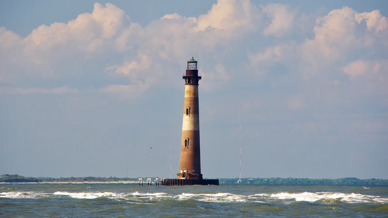 Morris Island Lighthouse standing alone in the water off Folly Beach at low tide – the lighthouse in the wide shots.